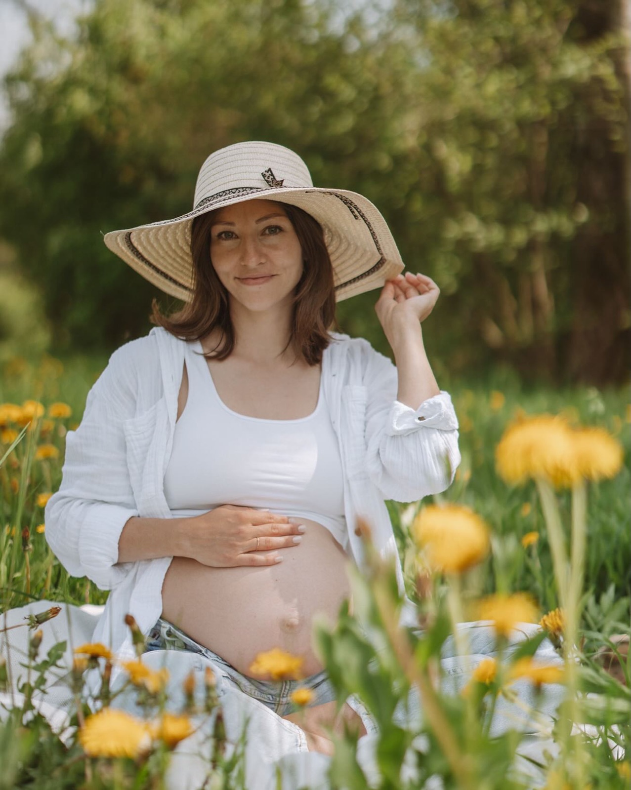 Schwangere Frau mit Hut in einer Blumenwiese